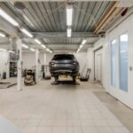 Well-lit garage with a car on a hydraulic lift ready for repair.