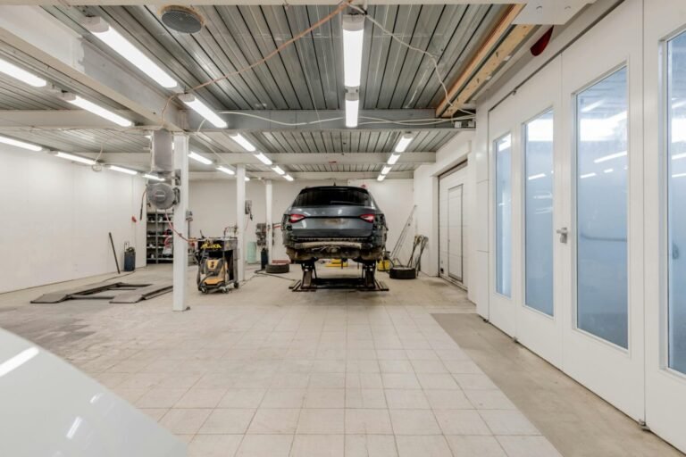 Well-lit garage with a car on a hydraulic lift ready for repair.