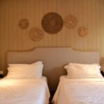Inviting hotel room with twin beds and artistic wooden wall decor.