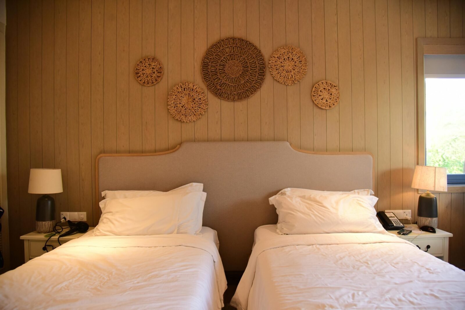 Inviting hotel room with twin beds and artistic wooden wall decor.