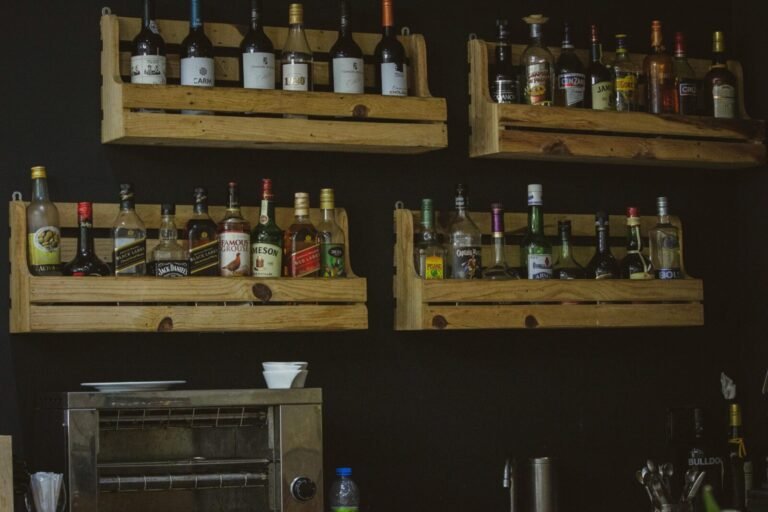 A rustic wooden shelf display of liquor bottles on a dark wall, perfect for a bar setting.